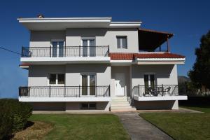 a large white house with a balcony and a yard at VILLAGE HOUSE in Tríkala