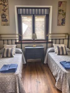 2 Betten in einem Zimmer mit Fenster in der Unterkunft La Fragua in Nueva de Llanes
