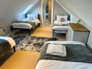 um quarto no sótão com 3 camas e uma escada em The Dairy, Bramble Farm Cottages em Ferndown