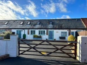 a white house with a wooden gate in front of it at The Dairy, Bramble Farm Cottages in Ferndown