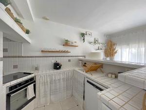 una cocina con electrodomésticos blancos y azulejos blancos en Maison Saintes-Maries-de-la-Mer, 3 pièces, 4 personnes - FR-1-475-112, en Saintes-Maries-de-la-Mer