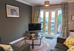 a living room with a couch and a tv at Stylish Modern Apartment, FREE SECURE Parking in Allesley