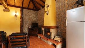ein Wohnzimmer mit einem Kamin und einem Kühlschrank in der Unterkunft Casa Quinta das Vessadas in Celorico de Basto