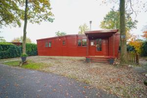 una casita roja en un patio con entrada en Better together - luxe chalet met houtkachel, en Erm