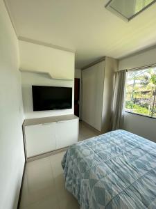 a bedroom with a bed and a flat screen tv at Flat Chácara Olhos D’Água in Gaspar