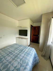 a bedroom with a blue bed and a television at Flat Chácara Olhos D’Água in Gaspar