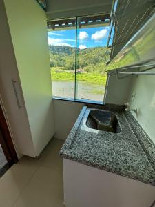 a kitchen with a sink and a window at Flat Chácara Olhos D’Água in Gaspar