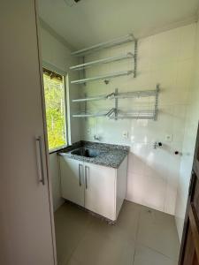 a white bathroom with a sink and a shower at Flat Chácara Olhos D’Água in Gaspar