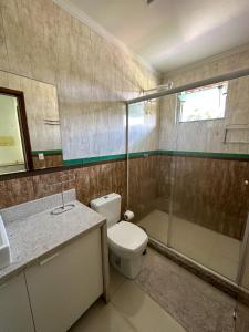 a bathroom with a toilet and a glass shower at Flat Chácara Olhos D’Água in Gaspar
