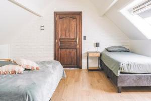 Schlafzimmer im Dachgeschoss mit 2 Betten und einer Holztür in der Unterkunft De Burkelhoeve app.A in Maldegem