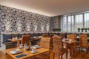 un comedor con mesas y sillas de madera y una pared de madera en Le Nouvel Hôtel en Oyonnax