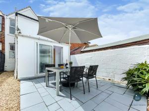 patio ze stołem, krzesłami i parasolem w obiekcie Sanderlings - holiday home close to beach w mieście Weymouth