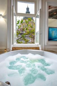 a bath tub filled with water in front of a window at ENZO CAPO VIP suite in Budapest