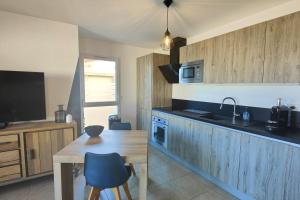 cocina con armarios de madera, mesa de madera y fregadero en Bright apartment - sea view, en Fréjus