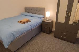 a bedroom with a bed with a lamp and a dresser at Comfortable 2 Mins from River & 5 Mins From Town in Kempston