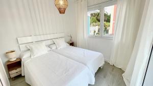 a white bedroom with a white bed and a window at The Cliffs - VilaTurquesa B in Viveiro