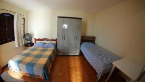 a bedroom with two beds and a cabinet at Casa da Olga Itatiaia in Itatiaia