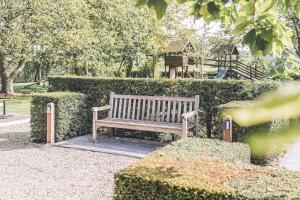 a wooden bench sitting in front of a hedge at De Burkelhoeve app.B in Maldegem