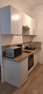 a kitchen with white cabinets and a microwave at Studio Winston in Dinard