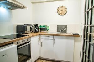 a kitchen with white cabinets and a clock on the wall at Joli studio plein centre in Châteauroux