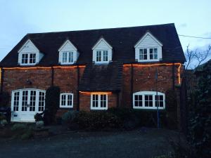a brick house with white windows and a black roof at Holly Cottage in Muxton