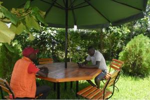 zwei Männer, die an einem Tisch unter einem Schirm sitzen in der Unterkunft The D'Lux Home, Homa Bay in Homa Bay