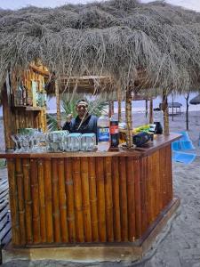a man sitting at a bar on the beach at Hermosa casa frentes al mar en Montanita con piscina in Montañita