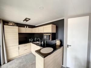eine Küche mit Holzschränken und einer schwarzen Arbeitsplatte in der Unterkunft Chalet standing, 6 couchages, piscine chauffée, terrasse privée, proche plage et commerces - FR-1-361-520 in Jullouville-les-Pins