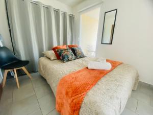 1 dormitorio con 1 cama con manta naranja y silla en Ma Terrasse Les Thermes Parking Wifi Un-Séjour-à-Part, en Clouange