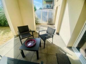 2 sillas y una mesa en un porche en Ma Terrasse Les Thermes Parking Wifi Un-Séjour-à-Part, en Clouange