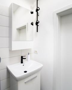 bagno bianco con lavandino e specchio di Mansarda Cotroceni a Bucarest