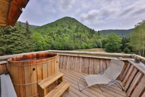 a wooden deck with a chair and a hot tub at ESCALE CAB'ÂNE in Mittlach