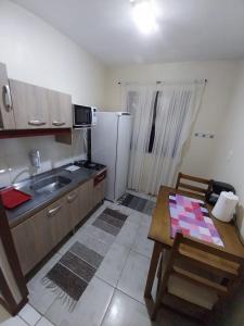 a small kitchen with a table and a refrigerator at Apartamento no centro in Canela