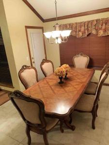 een eettafel met stoelen en een vaas met bloemen erop bij Spacious Oasis - 4 BDRM Top Luxury Home in Edmond! in Edmond