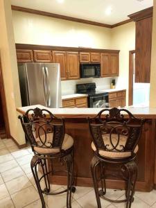 een keuken met 2 stoelen aan een aanrecht met een koelkast bij Spacious Oasis - 4 BDRM Top Luxury Home in Edmond! in Edmond