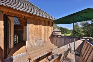a wooden cabin with a bench and an umbrella at ESCALE CAB'ÂNE in Mittlach
