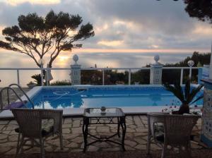 a swimming pool with two chairs and a table next to it at bb la guardiia in Anacapri