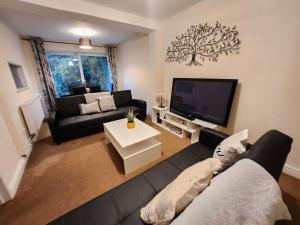 a living room with a black couch and a tv at Lovely Spacious Stays in Cambridge