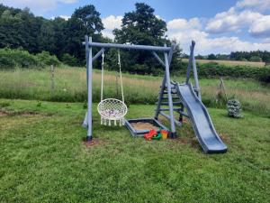 un parque infantil con tobogán y columpio en Domek Ostoja, en Łomnica