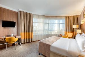 ein Hotelzimmer mit einem großen Bett und einem großen Fenster in der Unterkunft Diwan Rose Hotel in Medina