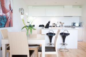 cocina blanca con mesa de comedor y sillas en Surfside 34 Zinc, en Newquay