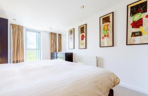 Un dormitorio con una cama blanca y algunas fotos en la pared en Surfside 34 Zinc, en Newquay