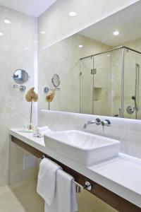 a white bathroom with a sink and a mirror at Adele Boutique Hotel in Pécs