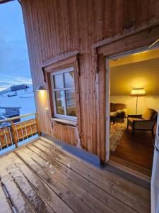 a porch of a wooden house with a living room at Villa Nestun - Northern lights villa with sauna in Selnes