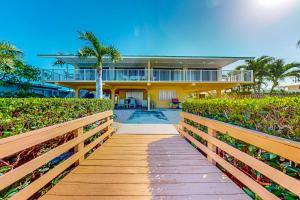 a wooden walkway leading to a yellow house at Sea Pointe on the Canal in Key Colony Beach