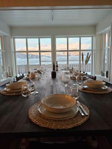 una mesa de comedor con vasos y platos. en Villa Nestun - secluded oasis near Tromsø city, en Selnes