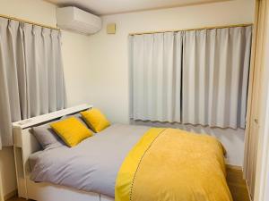ein Schlafzimmer mit einem Bett mit gelben Kissen in der Unterkunft Kamei House - Vacation STAY 07100v in Tokio