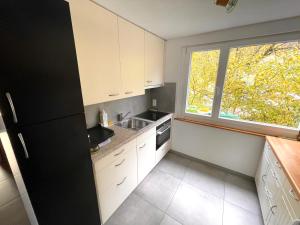 uma cozinha com um frigorífico preto e uma janela em Bellevue Apartment em Ringgenberg