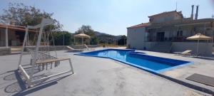 卡羅維西的住宿－Samos Villa With Pool，一座带椅子和遮阳伞的游泳池位于一座建筑旁边