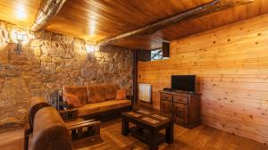 ein Wohnzimmer mit einem Sofa und einem TV in der Unterkunft Casa do Guardião do Castelo in Arnoia